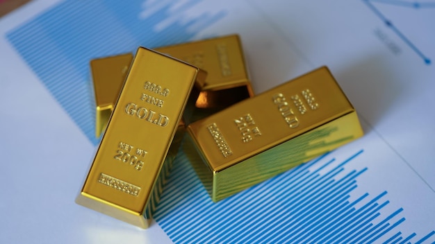 Gold bars on financial documents with charts and graphs closeup gold price exchange rates and