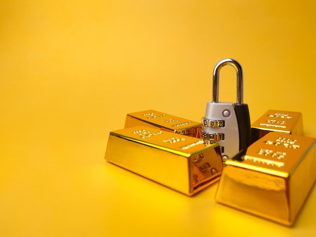 Gold bars and padlock financial concept and conceptual image on
a yellow background