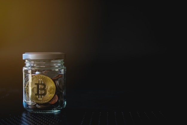 写真 黒の背景にガラス瓶の金ビットコインとお金のコイン暗号通貨と金融の概念