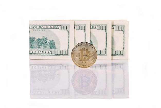 Фото Золотая монета биткойн стоит перед долларовыми банкнотами