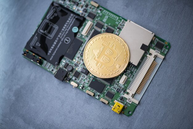 Foto bitcoin d'oro su una scheda di computer, su una superficie grigia. moneta elettronica