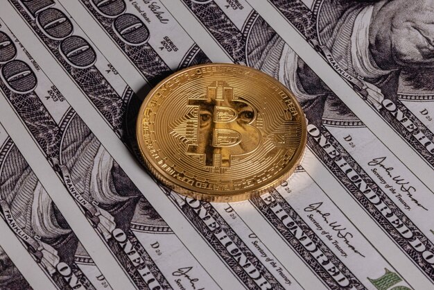 Gold bitcoin on one hundred dollar bills