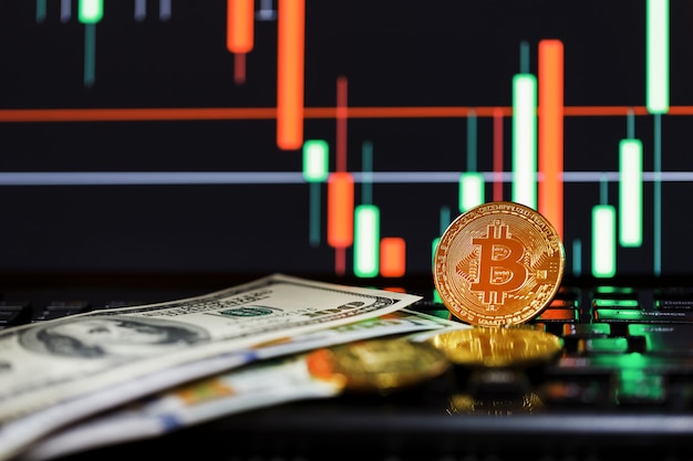 Bitcoin d'oro sullo sfondo di business grafici close-up e 100 banconote da un dollaro.