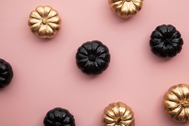 Gold and black pumpkins on pastel pink flat lay thanksgiving composition