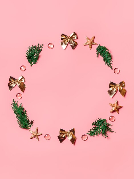 Gold bows twigs of Christmas tree  beads stars in the form of wreath on peachcolored background