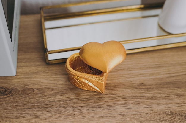 A gold box in the shape of a heart stands on the table