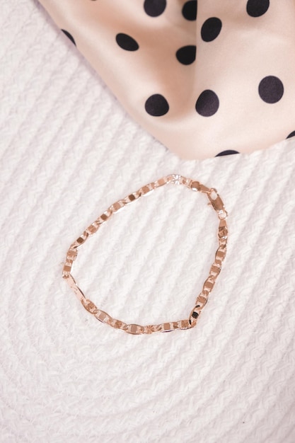 A gold bracelet with a black polka dot pattern is displayed on a white background.