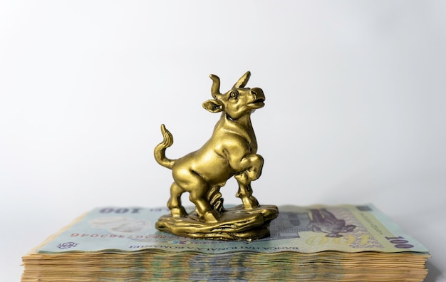 A gold bull statue sits on a stack of banknotes.