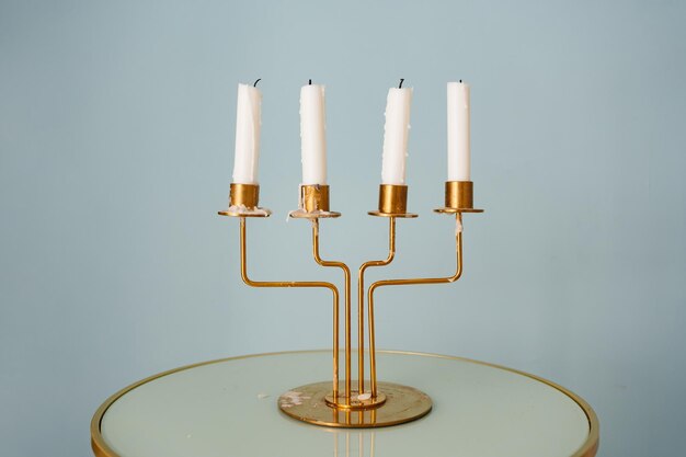 A gold candlestick for four candles on a round table against the background of the wall elements of decor in retro style