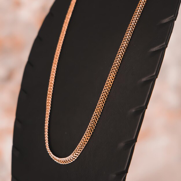 A gold chain necklace with a diamond design on it.