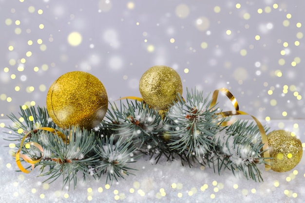 Золотые новогодние шары и золотой серпантин на светлом фоне с золотыми огнями боке