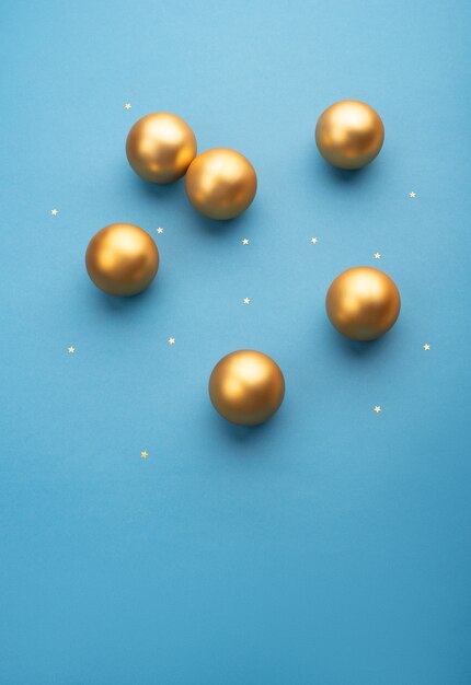 Gold Christmas balls on a light blue background with stars