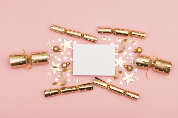 Gold Christmas cracker with a blank white label luxury gold festive cracker on a pastel pink background