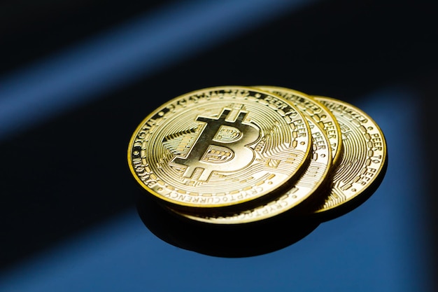 Monete d'oro di bitcoin sulla superficie del tavolo con vetro.