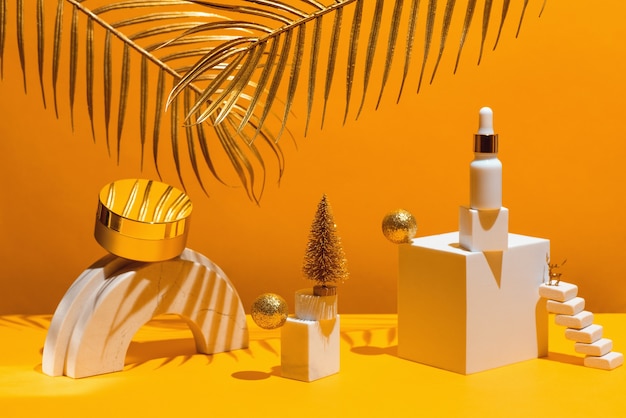 Gold composition with cream and serum, geometric shapes and Christmas tree