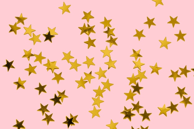 Gold confetti on a pastel pink surface