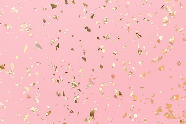 I coriandoli d'oro brillano su sfondo rosa pastello, lamina dorata, natale chic.