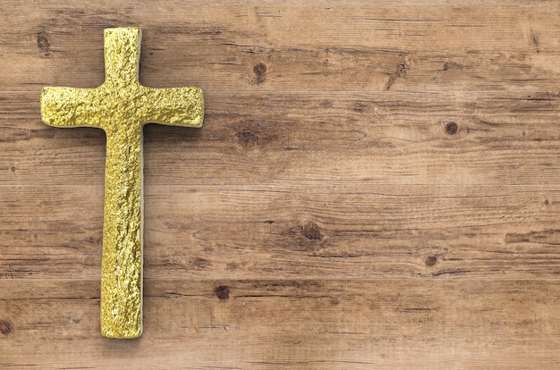 Gold cross with blank space on wooden background