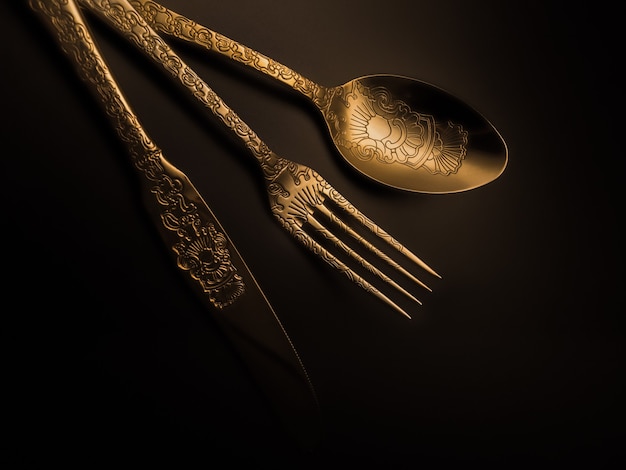 Gold cutlery with soft lighting from the side.