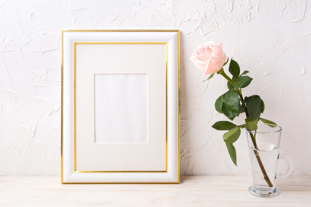 Gold decorated frame mockup with tender pink rose in glass