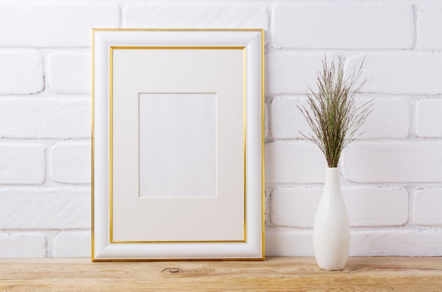 Cornice decorata in oro con erba scura in elegante vaso