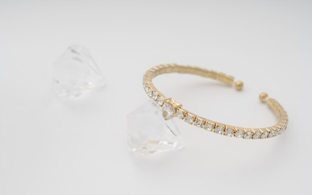 Bracciale a forma di cuore in oro e diamanti sul muro bianco