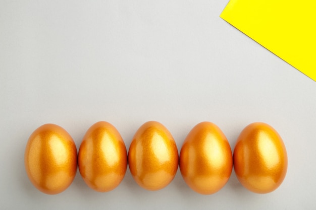 Gold Easter eggs on grey wall. Spring concept. Top view.