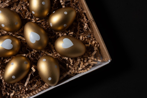 Gold eggs in paper box on black background