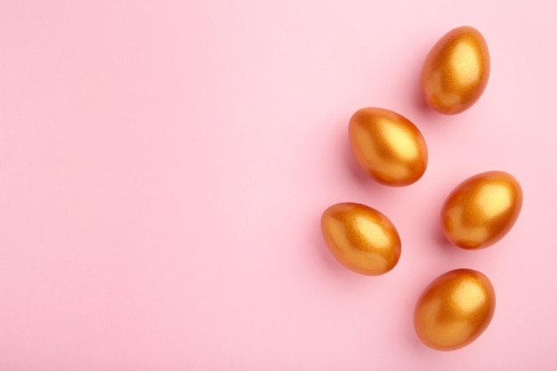 Gold eggs on the pink pastel wall. Easter concept.