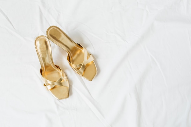 Gold female slippers shoes on white linen