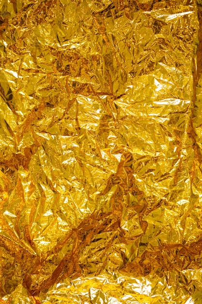 Фото Абстрактная морщинистая текстура золотой фольги крупным планом