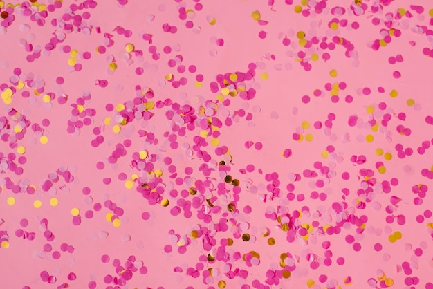 Gold and fuchsia confetti on a trendy pink pastel background A festive background for your projects