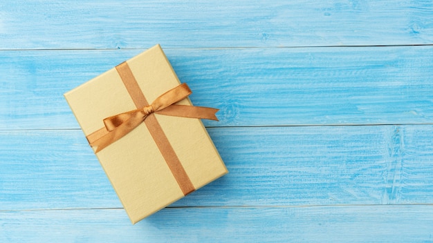 Gold gift box on a blue wooden table.