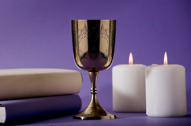 A gold goblet with a white candle next to it