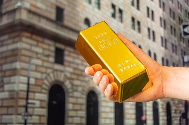 Gold ingot in hand on background Federal Reserve Bank of New York The building hosts a vault containing the world's largest depository of gold