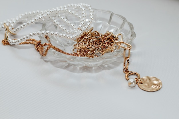 Gioielli in oro, blastet e una catena con perline e perle in un supporto di cristallo su uno sfondo grigio. contenuto aziendale.