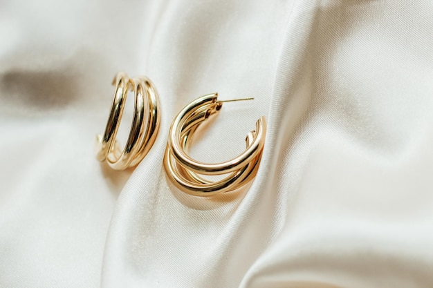 Gold jewelry earrings made of gold on the background of silk