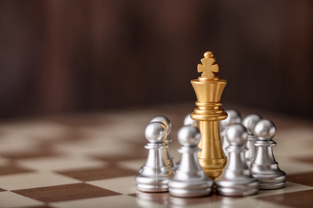 Gold king standing in the midst of chess on board