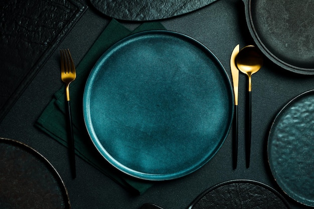 Photo gold knives and forks on a black background empty black plate beautiful gold cutlery view from above