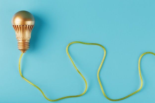 A gold light bulb with a gold wire on blue.