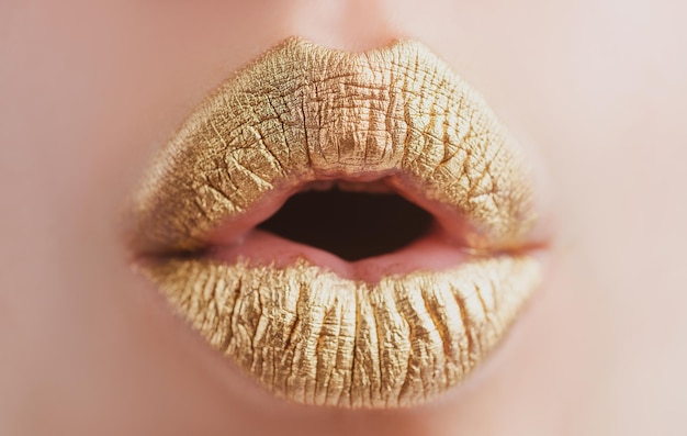 金色の唇女性は唇に金色の口紅でクローズアップキラキラ光沢のある唇を噛む