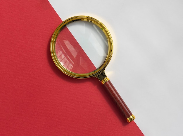 Photo gold magnifying lens over red and white background search tool