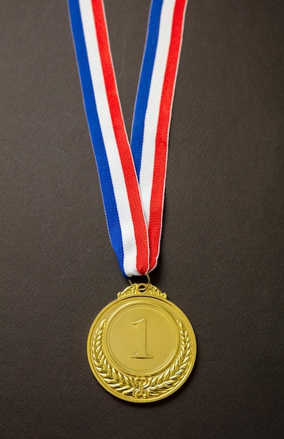 Gold medal Champion trophy award and ribbon Prize in sport for winner isolated on black background