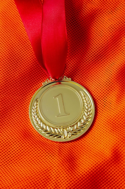 Gold medal Champion trophy award and ribbon Prize in sport for winner on orange shirt background