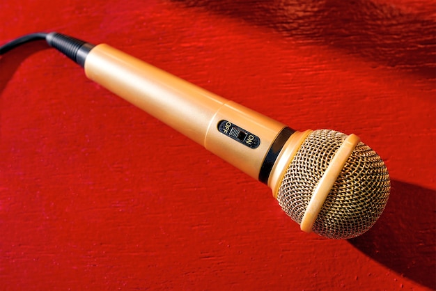 Gold microphone on red wooden and dark background with many\
lights