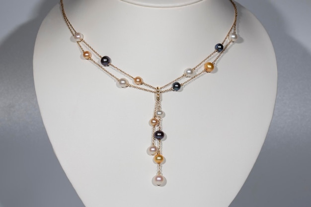 Gold necklace and multicolored pearls on a white stand jewelry jewelry art and pawnshop concept