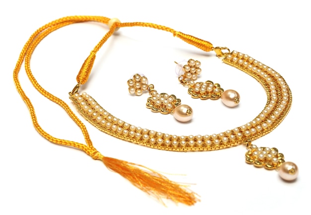 Gold necklace of pearl with earrings over white background