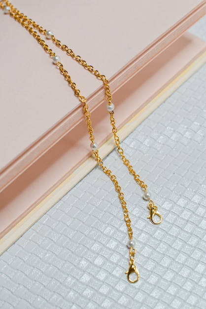 Gold necklace in white pink background