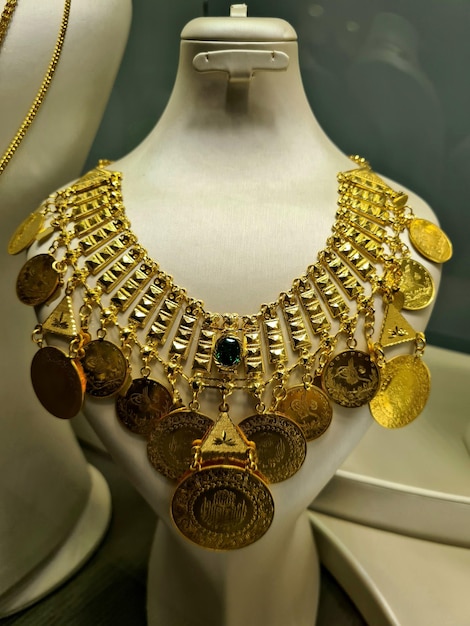 A gold necklace with coins on it is displayed in a store.