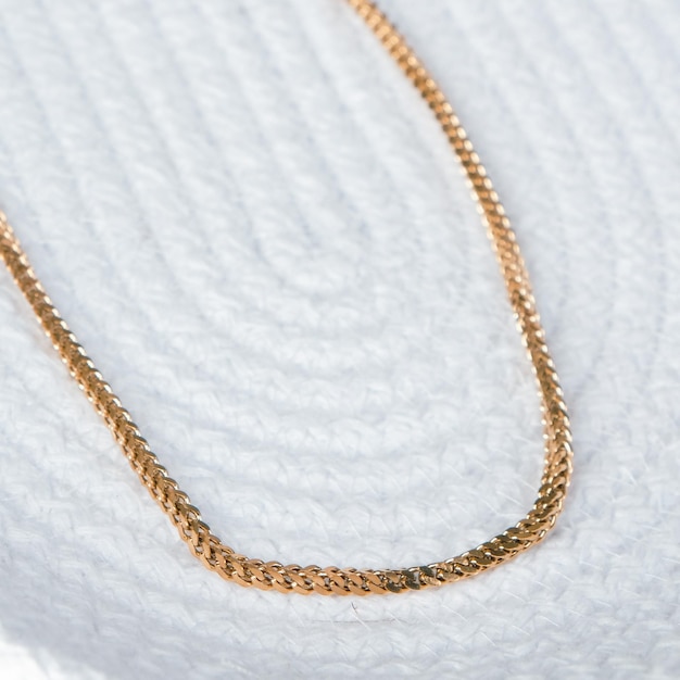 a gold necklace with a gold chain on it is laying on a white cloth.